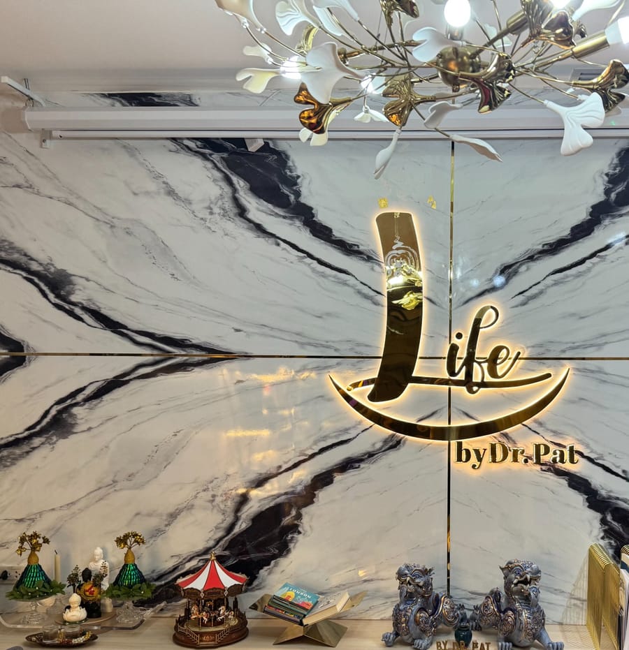 LIFE by Dr. Pat gold logo on the marble wall of the clinic